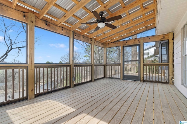 unfurnished sunroom featuring a healthy amount of sunlight, a ceiling fan, and vaulted ceiling