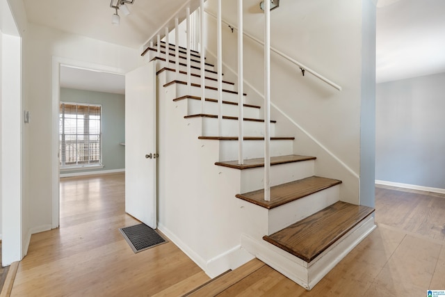 stairway with wood finished floors, visible vents, and baseboards