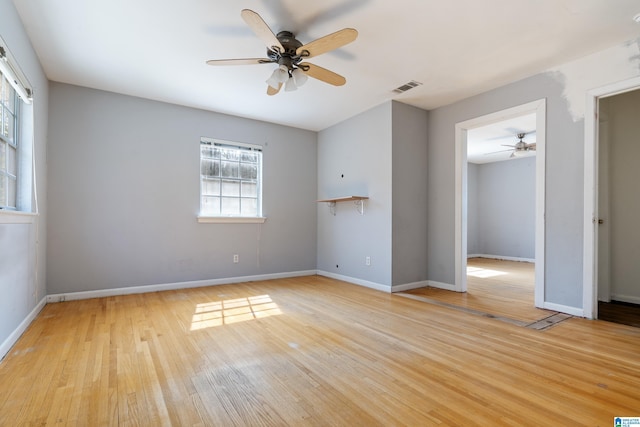 unfurnished room with visible vents, baseboards, wood finished floors, and a ceiling fan