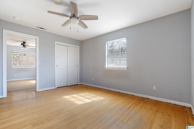 unfurnished bedroom featuring a closet, visible vents, light wood-style flooring, and baseboards