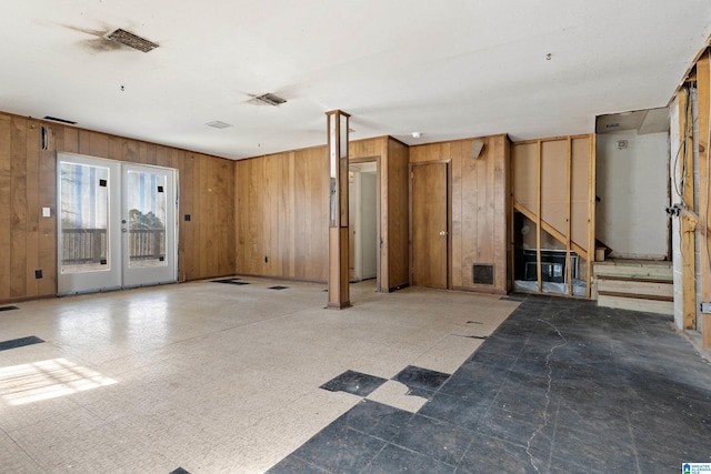 interior space with tile patterned floors, visible vents, and wooden walls