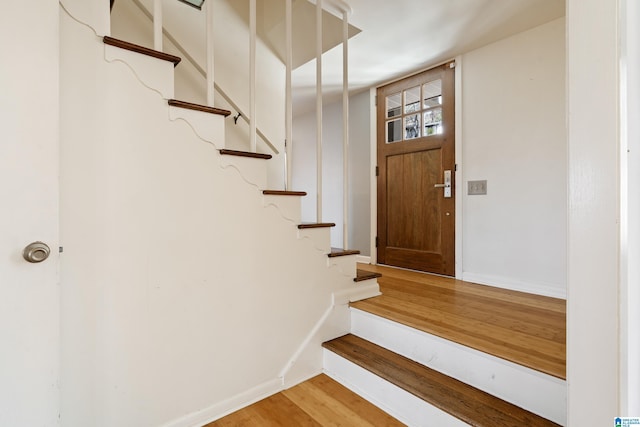 staircase featuring baseboards and wood finished floors