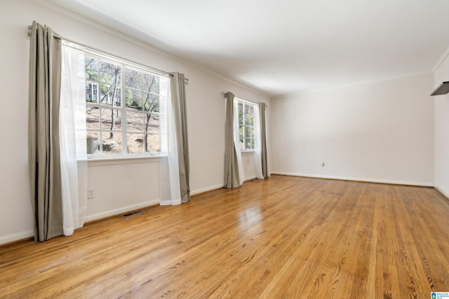 spare room with visible vents, baseboards, light wood-style floors, and crown molding