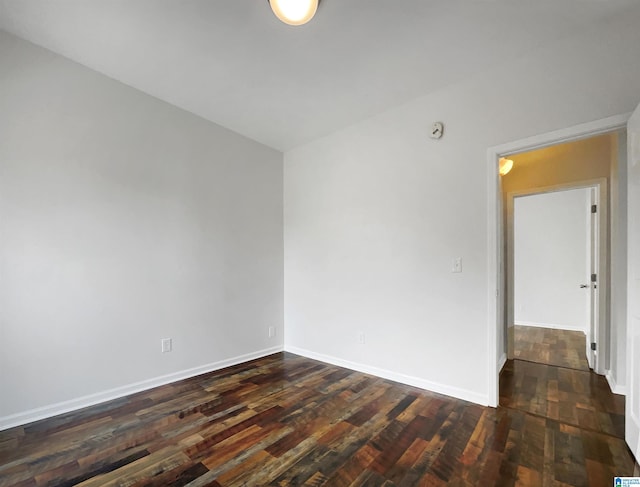 spare room featuring baseboards and dark wood-style flooring