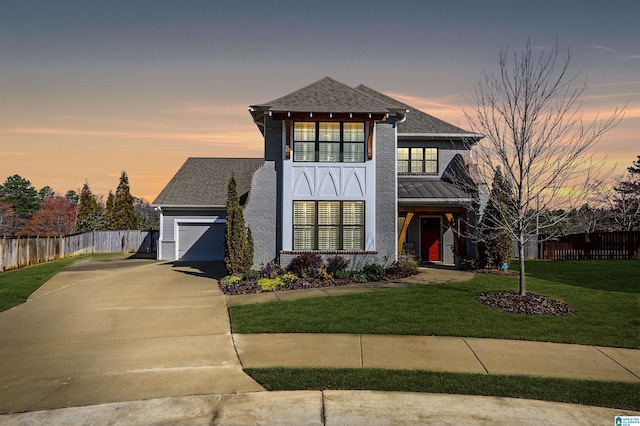 view of front of house with brick siding, fence, a lawn, a garage, and driveway