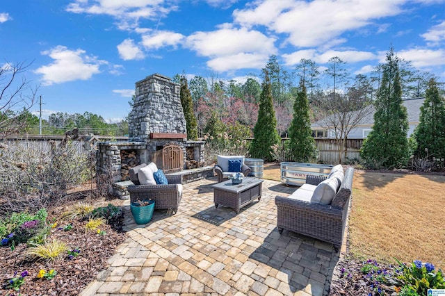 view of patio with an outdoor living space with a fireplace and fence