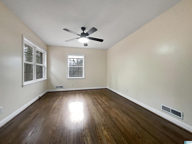 unfurnished room with dark wood-style floors, baseboards, and visible vents