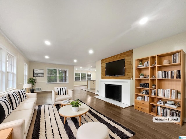 living room with a fireplace with flush hearth, recessed lighting, visible vents, and wood finished floors