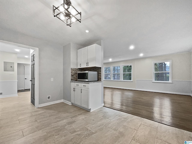 kitchen featuring electric panel, stainless steel microwave, white cabinets, and open floor plan