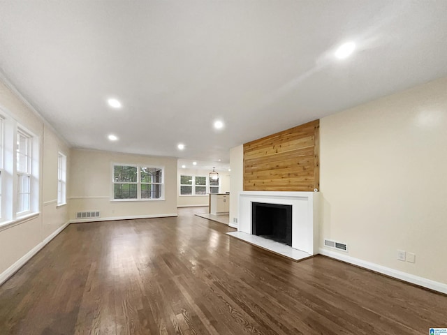 unfurnished living room featuring a fireplace with flush hearth, baseboards, visible vents, and dark wood-style flooring