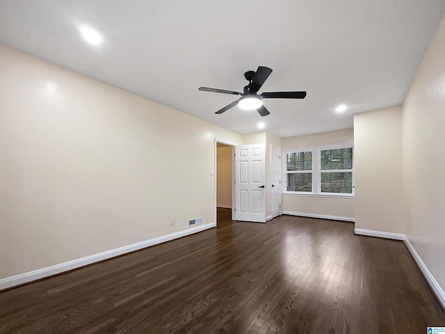 spare room featuring dark wood-style floors, visible vents, ceiling fan, and baseboards