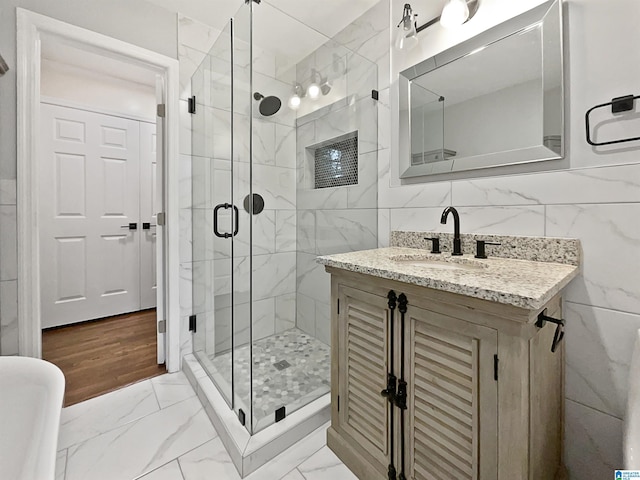 full bath with marble finish floor, tile walls, and a shower stall