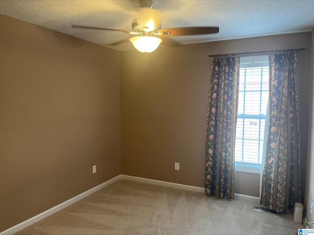 empty room with visible vents, baseboards, light colored carpet, a textured ceiling, and a ceiling fan