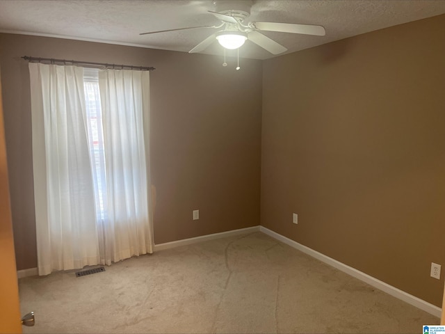 unfurnished room with a textured ceiling, baseboards, visible vents, and light carpet