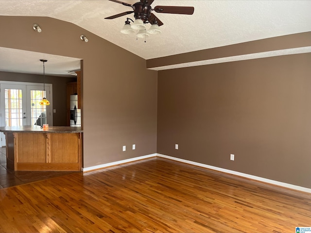 unfurnished living room featuring vaulted ceiling, french doors, dark wood-style flooring, and baseboards