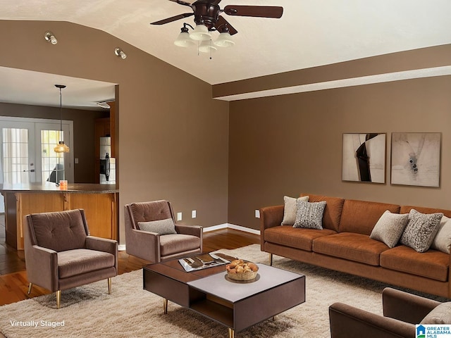 living area featuring french doors, baseboards, lofted ceiling, and wood finished floors