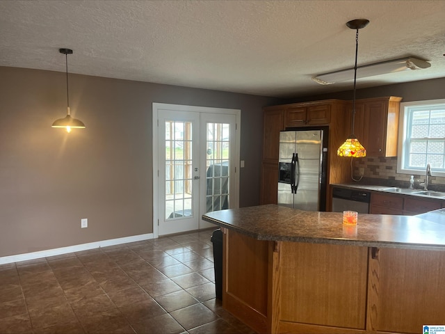 kitchen with backsplash, french doors, brown cabinetry, stainless steel appliances, and a sink