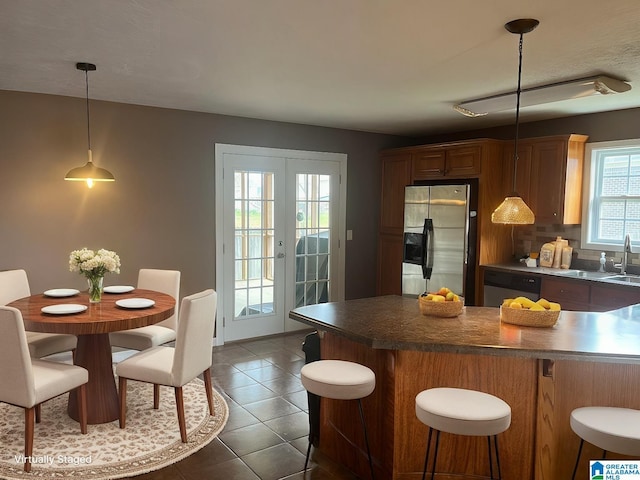 kitchen with dark tile patterned flooring, pendant lighting, french doors, stainless steel fridge with ice dispenser, and dishwasher