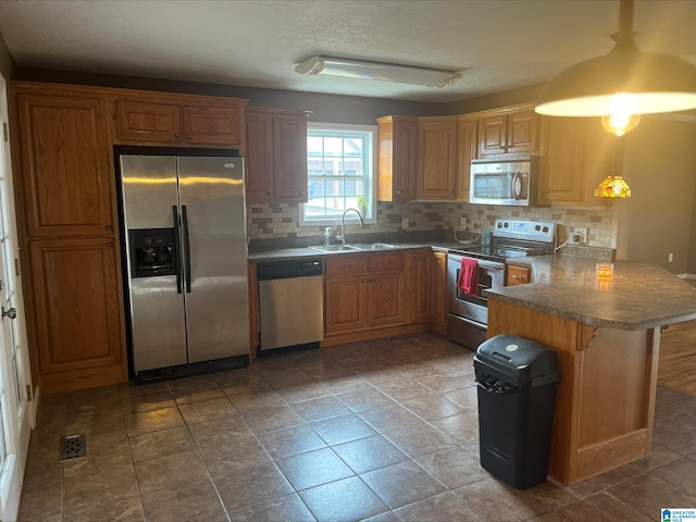 kitchen featuring decorative backsplash, a peninsula, a kitchen breakfast bar, stainless steel appliances, and a sink