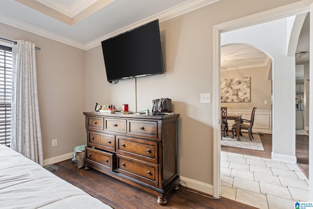 bedroom with arched walkways, dark wood-style floors, crown molding, and baseboards