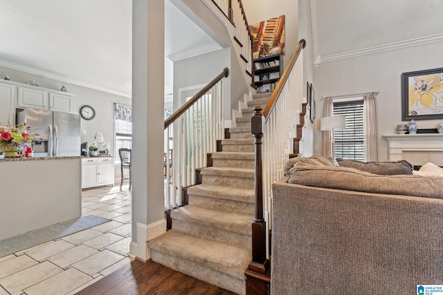 stairs with plenty of natural light, wood finished floors, and crown molding