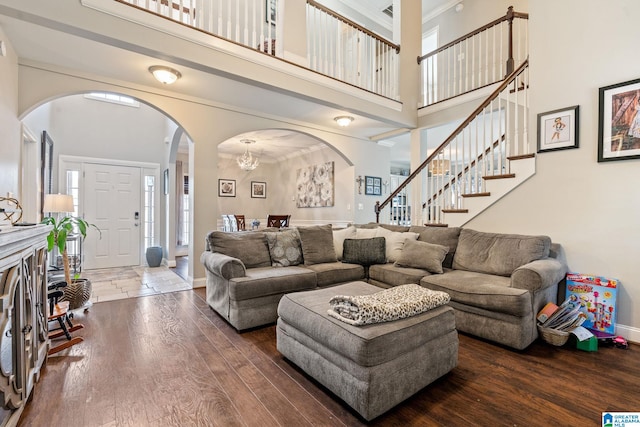 living room with hardwood / wood-style flooring, a high ceiling, and arched walkways