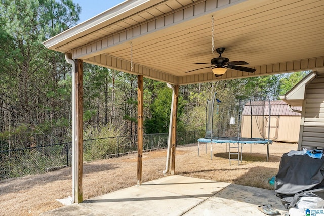 view of patio featuring an outbuilding, a fenced backyard, ceiling fan, a storage unit, and a trampoline