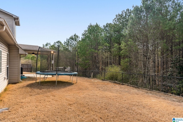 view of yard featuring a trampoline and fence