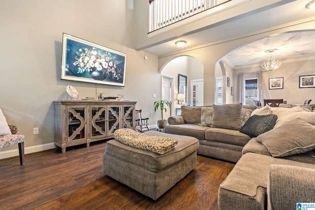 living room featuring a notable chandelier, wood finished floors, arched walkways, baseboards, and a towering ceiling