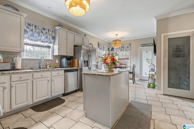 kitchen with ornamental molding, decorative backsplash, a sink, appliances with stainless steel finishes, and a center island