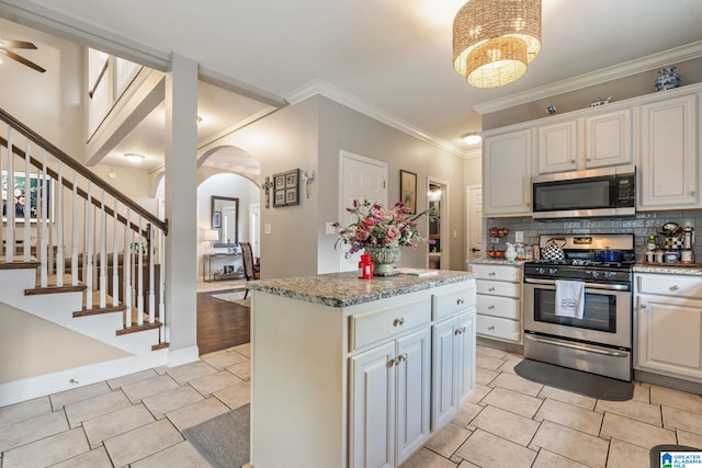 kitchen featuring backsplash, a center island, arched walkways, appliances with stainless steel finishes, and ceiling fan