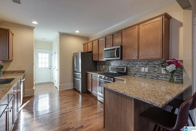 kitchen with light stone countertops, a peninsula, stainless steel appliances, dark wood-type flooring, and tasteful backsplash