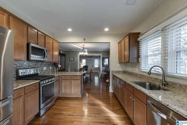 kitchen featuring a sink, backsplash, wood finished floors, stainless steel appliances, and a peninsula