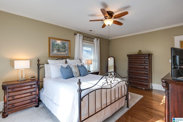 bedroom featuring ceiling fan, wood finished floors, baseboards, and ornamental molding