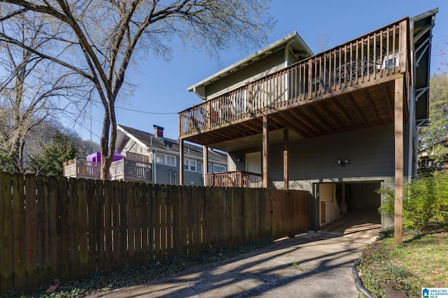 exterior space featuring driveway, a deck, and fence