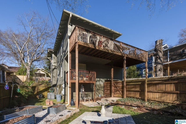 rear view of house featuring a deck, a garden, and fence private yard