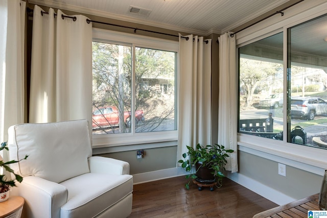 sitting room featuring visible vents, baseboards, wood finished floors, and ornamental molding