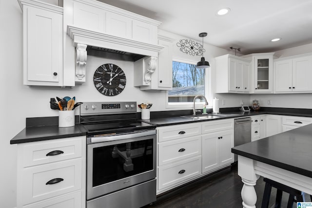 kitchen with dark countertops, white cabinets, stainless steel appliances, and a sink