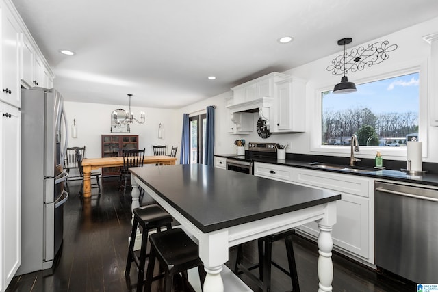 kitchen featuring dark countertops, dark wood finished floors, recessed lighting, appliances with stainless steel finishes, and white cabinetry