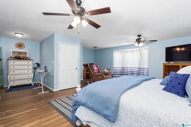 bedroom featuring wood finished floors, baseboards, freestanding refrigerator, and ceiling fan