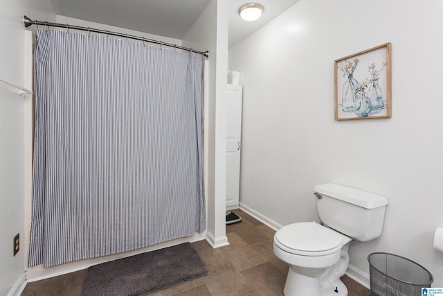 bathroom with a shower with shower curtain, baseboards, and toilet