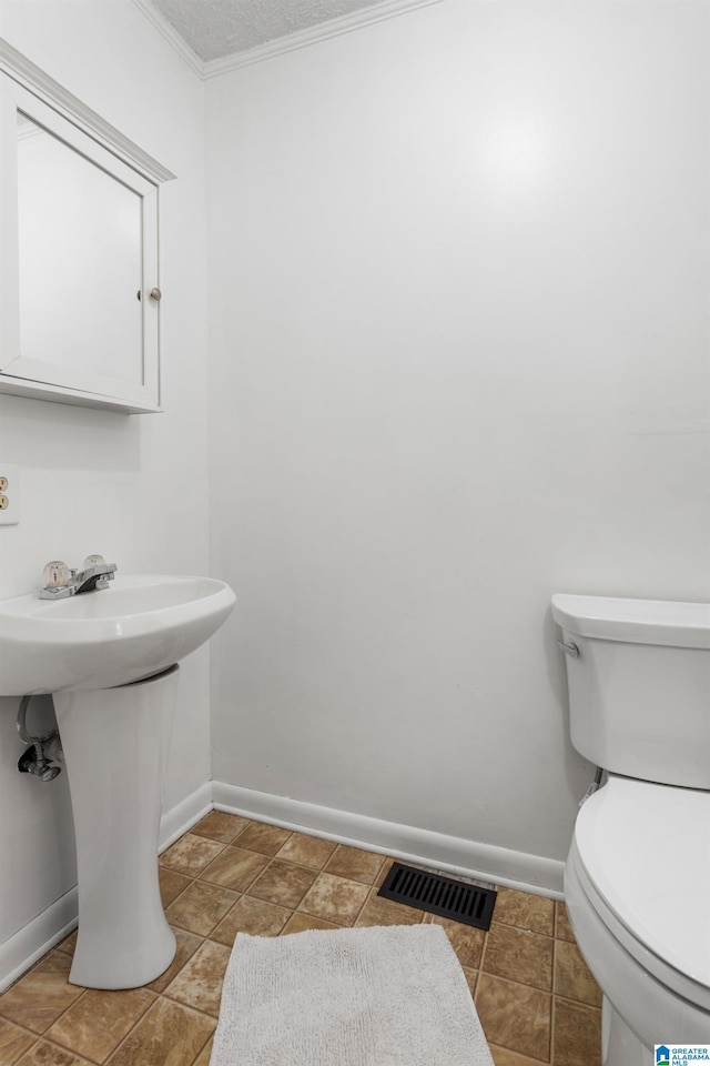 bathroom with tile patterned floors, visible vents, toilet, crown molding, and baseboards