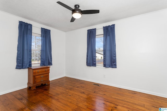 unfurnished room with visible vents, a ceiling fan, baseboards, and wood-type flooring