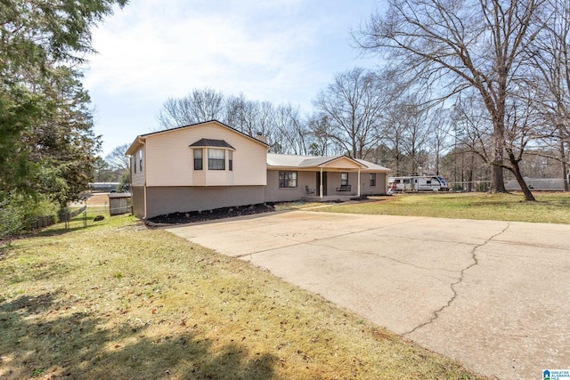 split level home with brick siding, concrete driveway, a front lawn, and fence