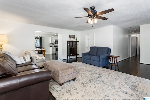 living area with dark wood-style floors, a ceiling fan, baseboards, and a textured ceiling