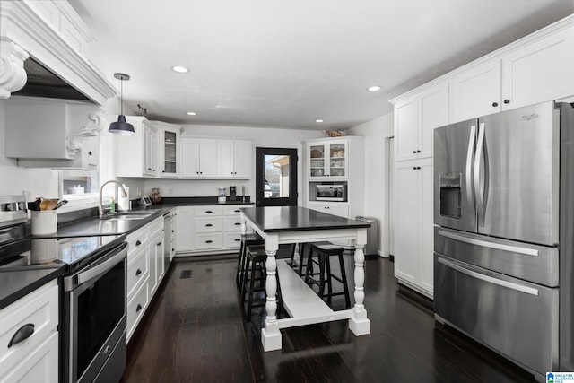 kitchen with stainless steel appliances, dark countertops, white cabinets, and dark wood-style flooring