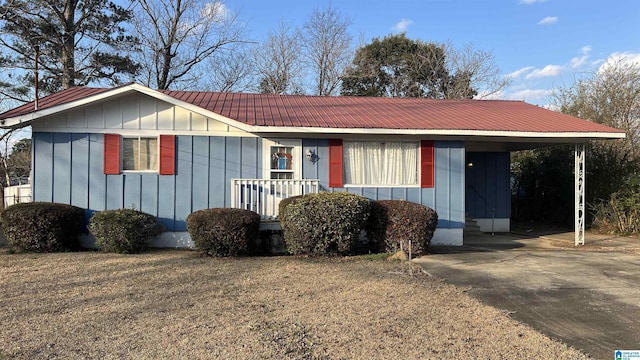 ranch-style home with metal roof, board and batten siding, and concrete driveway