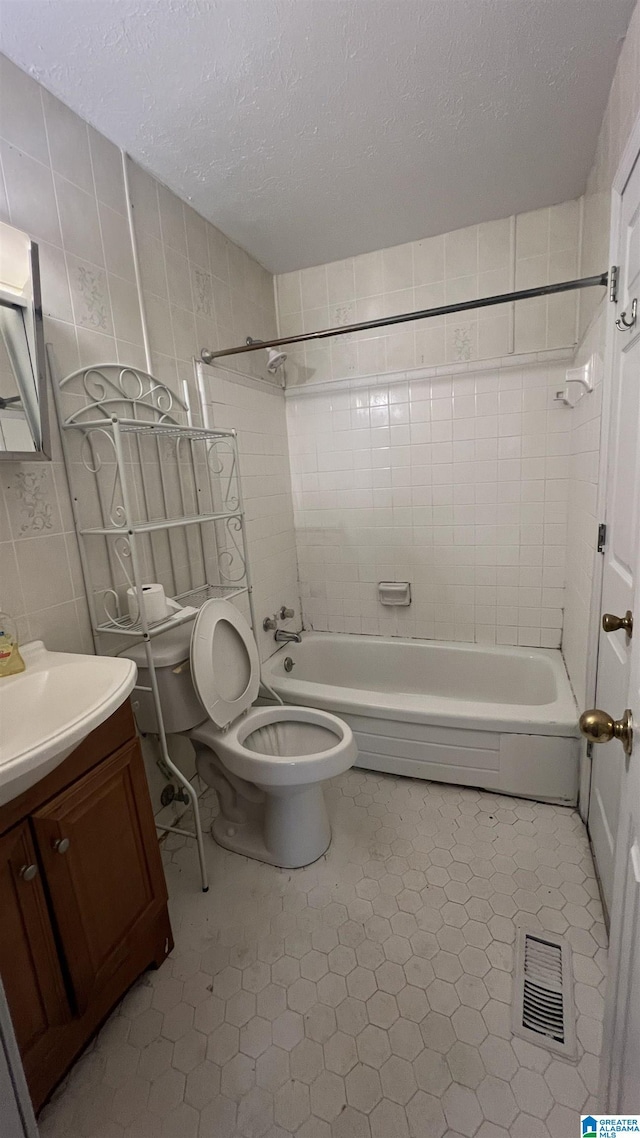 full bathroom with visible vents, tile walls, shower / washtub combination, vanity, and a textured ceiling