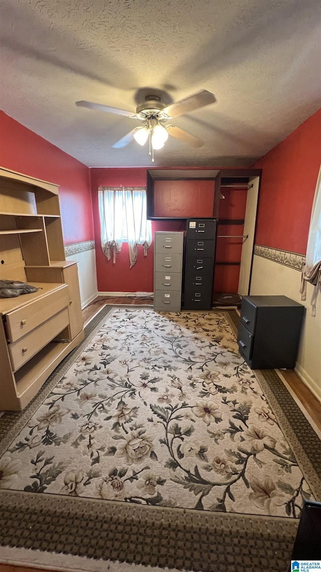 bedroom with baseboards, a textured ceiling, and a ceiling fan