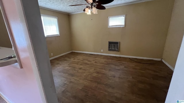 empty room featuring heating unit, baseboards, a wealth of natural light, and a textured ceiling